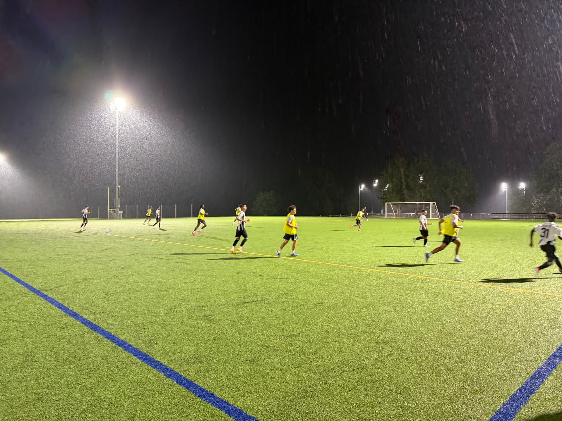 NC United FC and PFM FC players spread across a floodlit field as rain falls during the August 27 preseason friendly