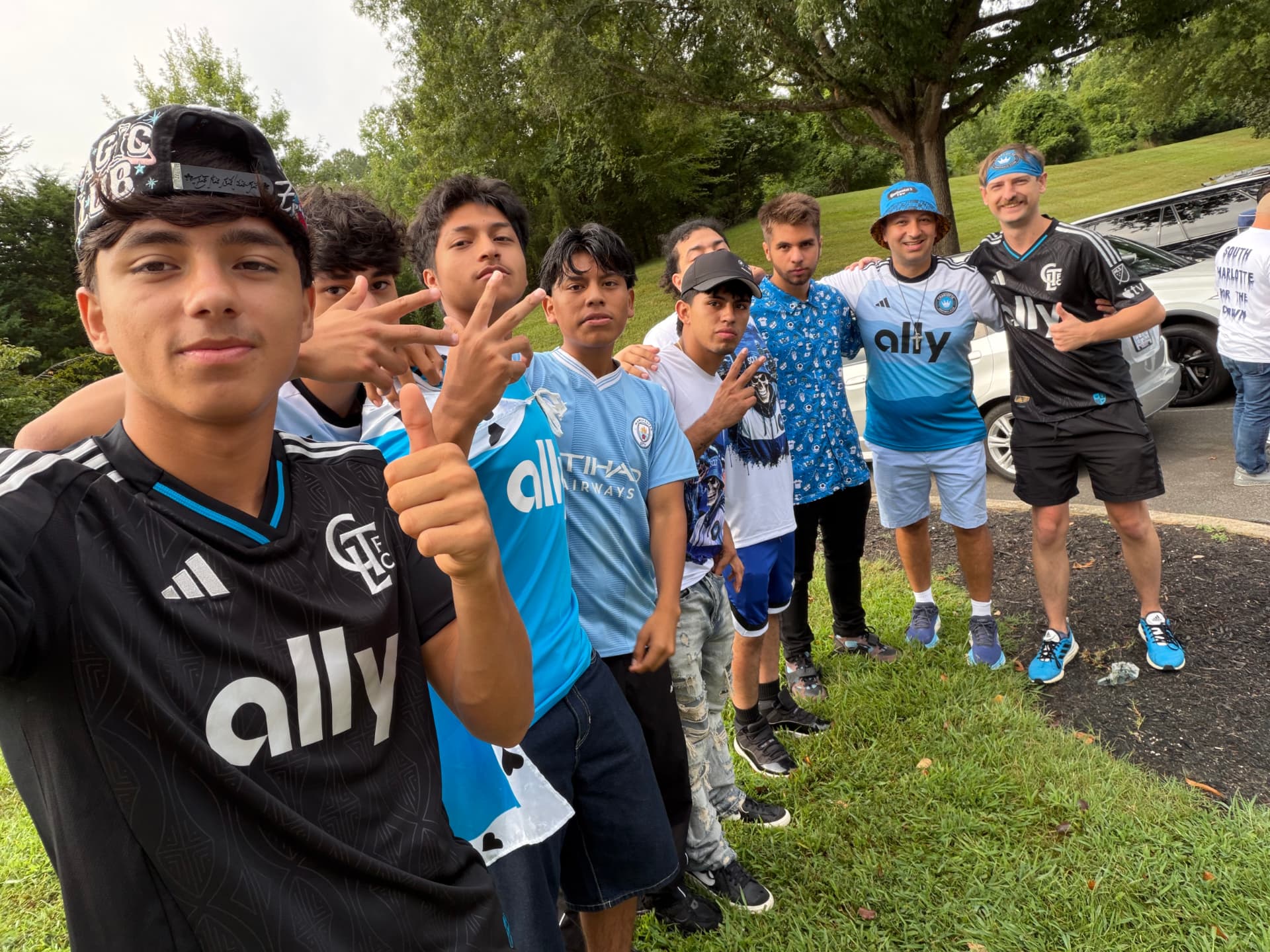 NC United FC members posing together with South Charlotte supporters in the parking lot before departure